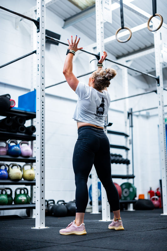 A photo showing a girl wearing The Defiant Co performance leggings whilst performing a workout, thus demonstrating their ability to stand up to the most rigorous of tests.  The leggings have The Defiant Co logo across the back of the waistband and are 7/8’s in length.  The colour is black.