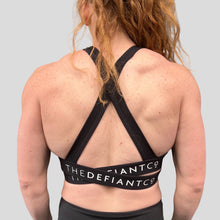 Load image into Gallery viewer, A photo showing the back of the amazing The Defiant Co Infinity Sports Bra.  The bra has a unique crossed back with The Defiant Co logo across both straps giving it a really standout look. The colour is black. 