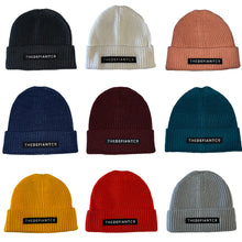 Load image into Gallery viewer, A collage showing a selection of beanie hats in a variety of colours. The hats have a ribbed finish with a roll cuff.  The cuff has The Defiant Co logo embroidered on the centre of the front in white on a black background. 