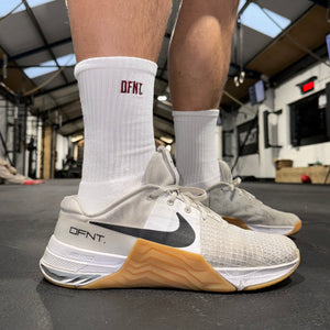 Unisex activewear socks spanning sizes 6-11.  The socks are white in colour and have a subtle DFNT. logo embroidered in burgundy designed to be facing out on the sock. When pulled up the socks sit around the lower part of the shin.