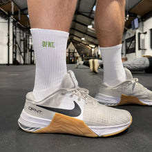 Load image into Gallery viewer, Unisex activewear socks spanning sizes 6-11.  The socks are white in colour and have a subtle DFNT. logo embroidered in olive green designed to be facing out on the sock. When pulled up the socks sit around the lower part of the shin.