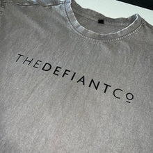 Load image into Gallery viewer, A photo showing an oversized The Defiant Co T-Shirt.  The shirt has the famous ‘The Defiant Co’ logo across the front of the chest.  The shirt has a round neck and is oversized.  This particular version has a washed finish and is the colour asphalt with black print.