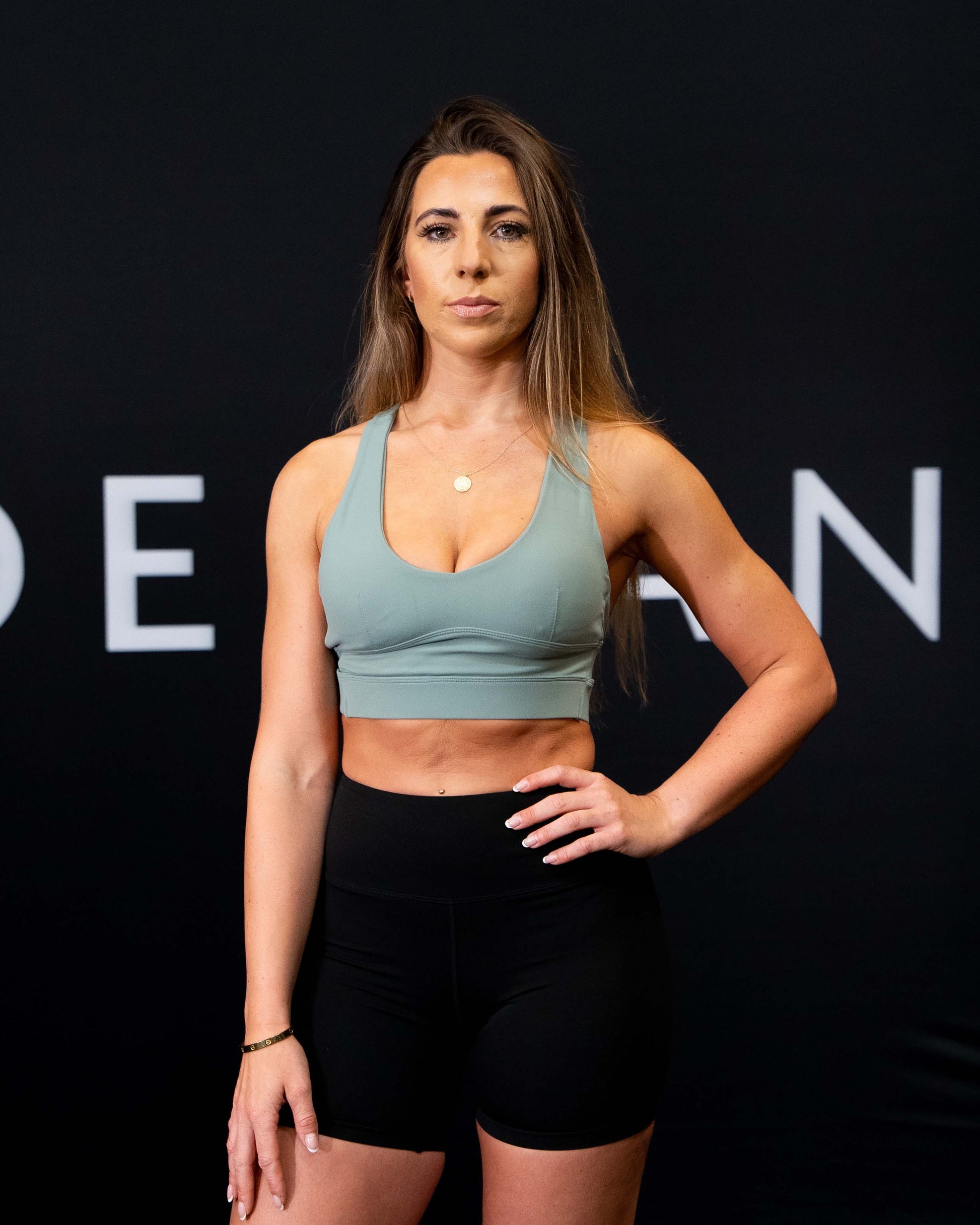 A girl against a black The Defiant Co backdrop wearing the Eternal 6 inch booty shorts.  The high waist and breathable material makes them perfect for any workout.  The colour is jet black.