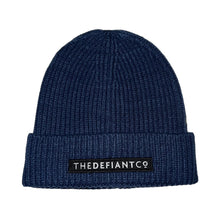 Load image into Gallery viewer, A photo showing a beanie hat. The hat has a ribbed finish with a roll cuff.  The cuff has The Defiant Co logo embroidered on the centre of the front in white on a black background. The beanie hat is steel blue.